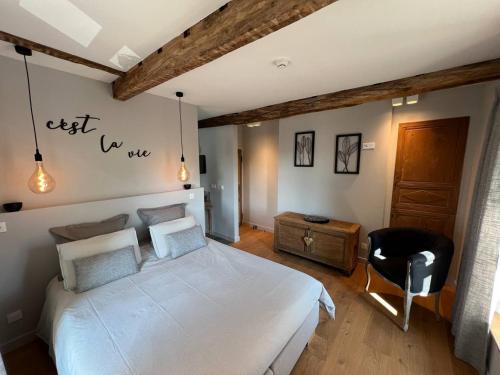 a bedroom with a white bed and a black chair at Maison Jean-Phi in Libin