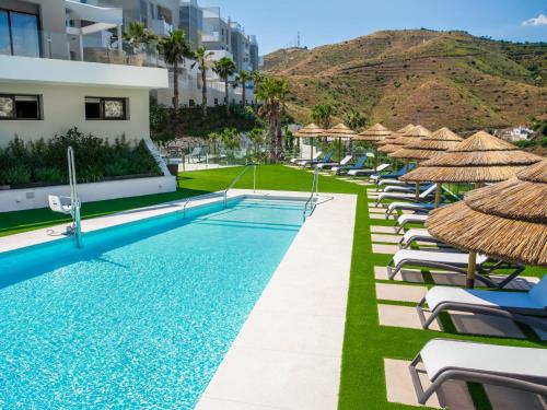an infinity pool with chairs and umbrellas at a resort at Apartment Collection View Free Spa & Padel by Interhome in Torrox Costa