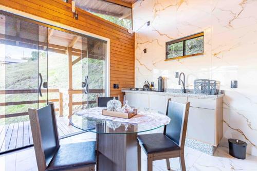 a kitchen with a glass table and chairs in a room at Cabana em Alfredo Wagner - Cabana Herança Serrana in Barracão