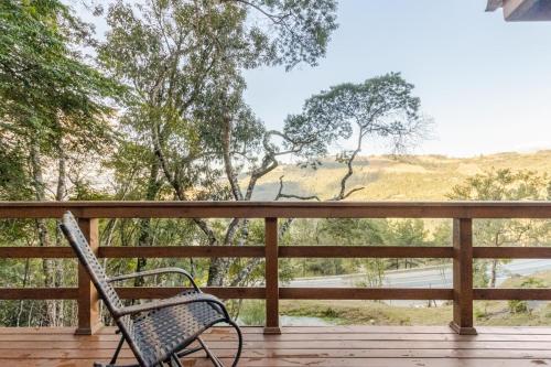 a chair sitting on a deck with a view of the mountains at Cabana em Alfredo Wagner - Cabana Herança Serrana in Barracão