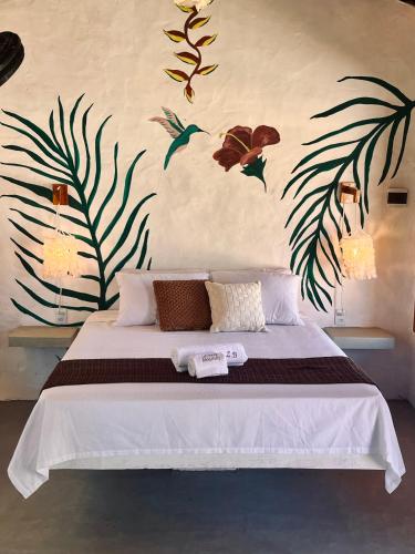 a bedroom with a bed with leaves and flowers on the wall at Zema Bangalôs in Trairi