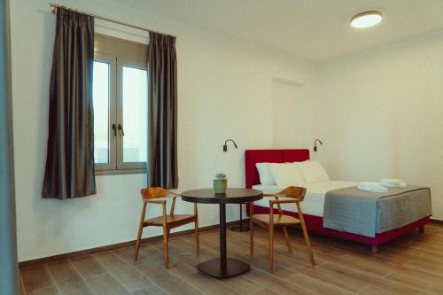 a hotel room with a bed and a table and chairs at Ollenia's Harmony Luxury Apartments in Derveni