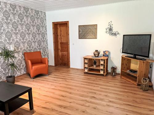 a living room with a television and a chair at Apartment Krüger-2 by Interhome in Großheide