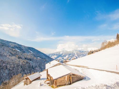 a building covered in snow with mountains in the background at Apartment Dinkl by Interhome in Stummerberg