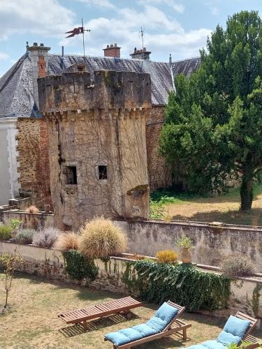 an old building with two chairs in a yard at Maison Tyto Alba in Saint-Victurnien