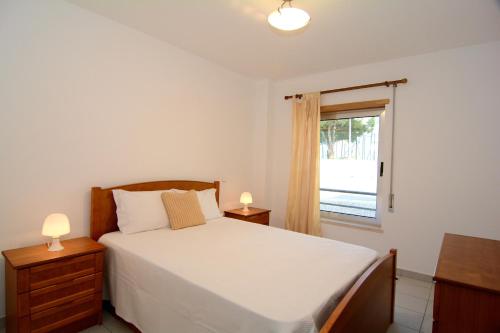 sypialnia z białym łóżkiem i oknem w obiekcie Apartamentos Encosta da Marina - Praia da Rocha w mieście Portimão
