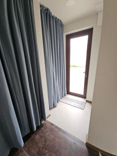a room with blue curtains and a window at IKI-IKI Apartments in Melnragė