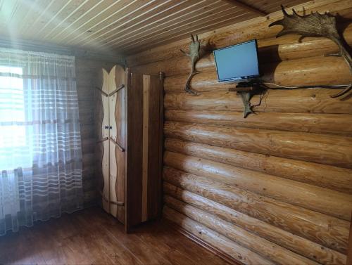 a room with a log wall with a tv on it at Лісовик in Synevyrsʼka Polyana