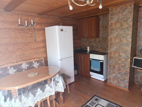 a kitchen with a white refrigerator and a wooden table at Лісовик in Synevyrsʼka Polyana