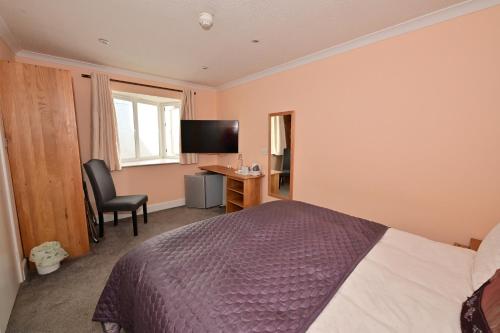 a bedroom with a bed and a desk and a television at Lyme Bay House in Dawlish