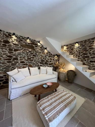a living room with a white couch and a stone wall at Estrella house in Kithnos