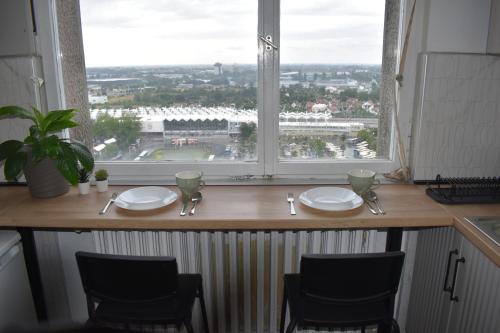 a table with plates and chairs in front of a window at Zatvoreno in Novi Sad