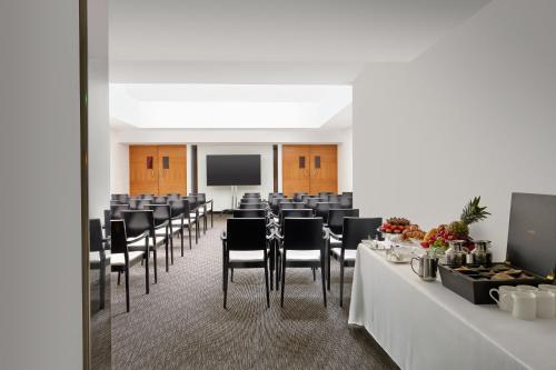 a conference room with tables and chairs and a screen at COMO Metropolitan London in London