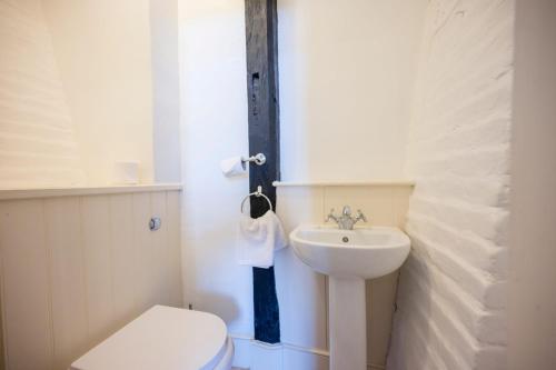 Un baño blanco con inodoro y lavabo. en Wool Room, Merchant House, Ipswich, en Ipswich