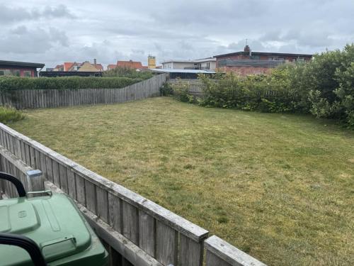 a yard with a fence and a grass field at Holiday Home Antine - 400m from the sea by Interhome in Thyborøn