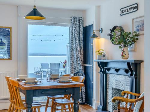 a dining room with a table and chairs and a fireplace at Tyr Llyr in Penclawdd