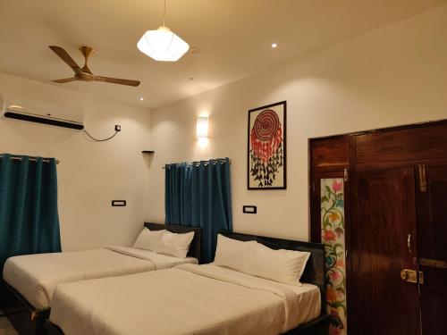 zwei Betten in einem Zimmer mit blauen Vorhängen in der Unterkunft La Goodwill Garden Luxury -pondicherry in Auroville