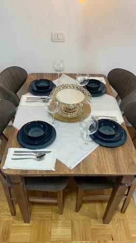 a wooden table with plates and wine glasses on it at Shala Apartments in Prizren