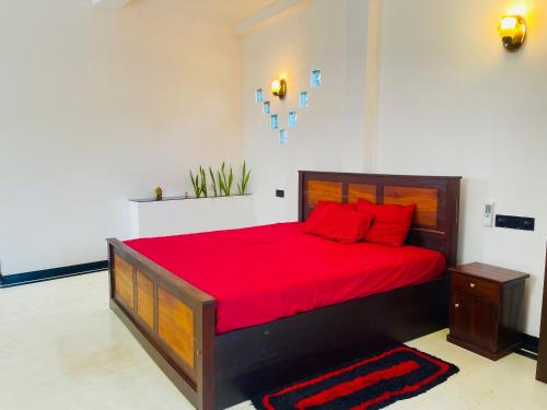 a bedroom with a large bed with red pillows at Rest N surf Apartments in Ahangama