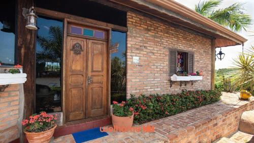 a brick house with a wooden door and some flowers at Casa de campo em Itupeva com vista para montanha in Itupeva