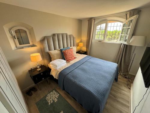 a bedroom with a bed with a blue blanket and two windows at Sea view villa - South facing - Grimaud, France in Port Grimaud