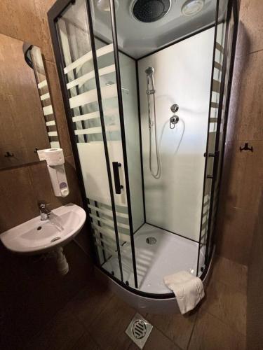 a bathroom with a glass shower and a sink at Tulipan Hotel Aquapark in Vyshkove