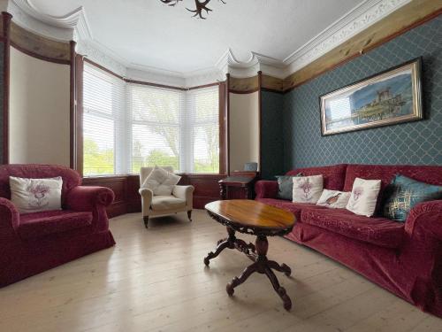 a living room with a red couch and a table at Stanford House in Inverness