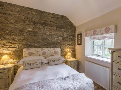 a bedroom with a bed and a stone wall at Walkmill Lodge in Wentnor