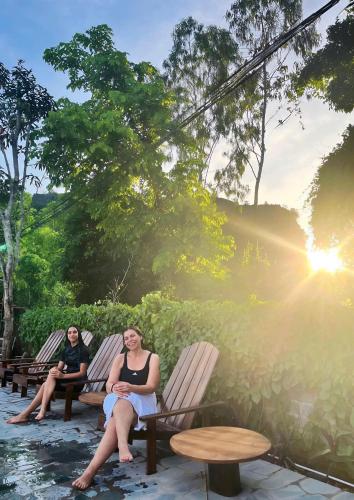 two women sitting on benches on a patio at Chilling Homestay - Hotel in Vũ Lâm