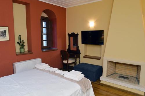 a bedroom with a white bed and a fireplace at Archontiko Leontari in Leondari