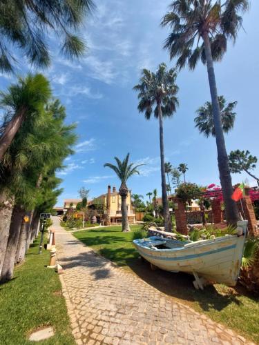 a boat sitting on a path next to palm trees at Villa Bora-Bora in Pêra