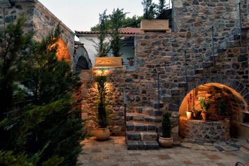 a stone building with an arch with potted plants at Archontiko Leontari in Leondari
