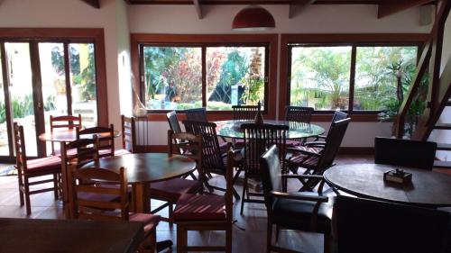 a restaurant with tables and chairs and windows at 3 Palmeiras Guest Lounge in Miguel Pereira