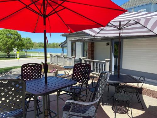 two tables and chairs with red umbrellas on a porch at Inns at St Albans in Saint Albans