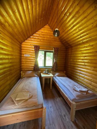 a bedroom with two beds in a wooden room at Casutele Ariesene in Arieşeni