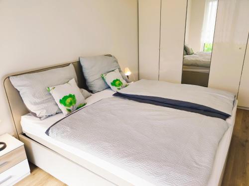 a white bed with green pillows in a bedroom at TOP Ferienwohnung Rosanna - Adults only in Graz