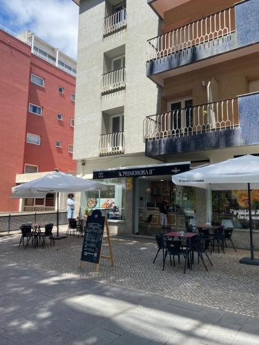 a patio with tables and umbrellas in front of a building at Casa Os Três Meninos in Fátima