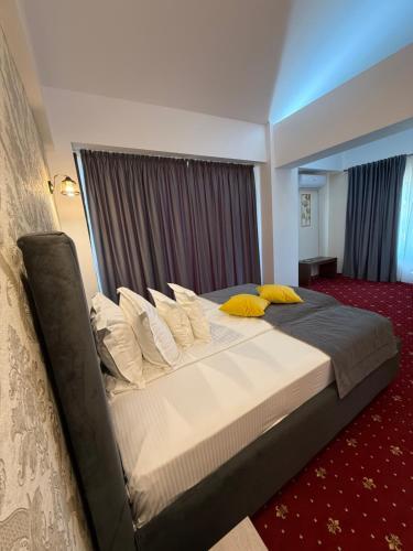a bedroom with a large bed with yellow pillows at Vila Premiere Bistro-Spa in Piatra Neamţ