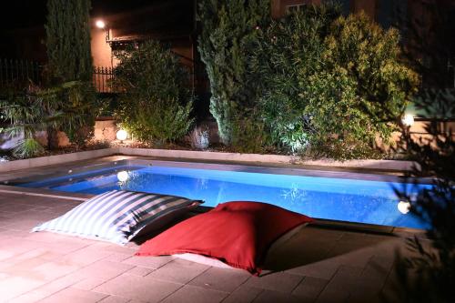 a swimming pool with a red pillow next to it at Relais des Vignerons, Chambres d'hôtes in Conilhac-Corbières