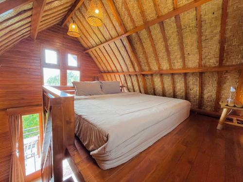 a bed in a room with a wooden ceiling at Murna House 1, Rooftop Balinese wooden house 360 sunrise to sunset view in Uluwatu