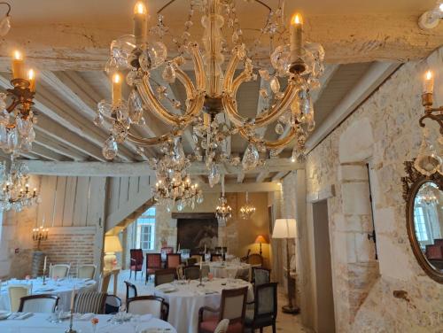 a dining room with a chandelier and tables at Les communs du Château du Sollier - Charme Calme Confort Climatisation à 5mn du péage in Bourges