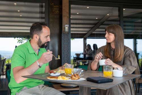 a man and woman sitting at a table eating food at La Ginestra in Fiore Camere in Sirolo