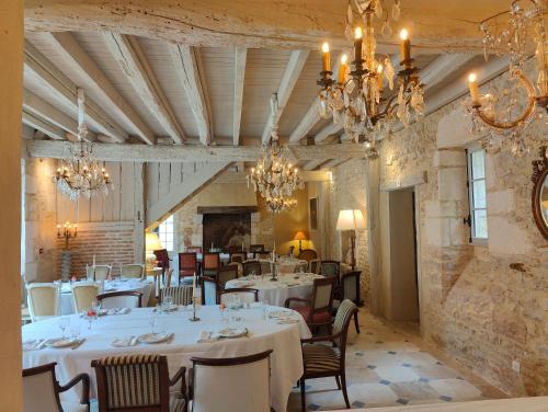 un restaurant avec des tables et des chaises blanches et des lustres dans l'établissement Le Château du Sollier - Charme calme et confort climatisation à 5mn du peage, à Bourges