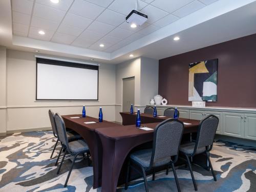 a conference room with a table and chairs and a projection screen at voco Sarasota by IHG in Sarasota