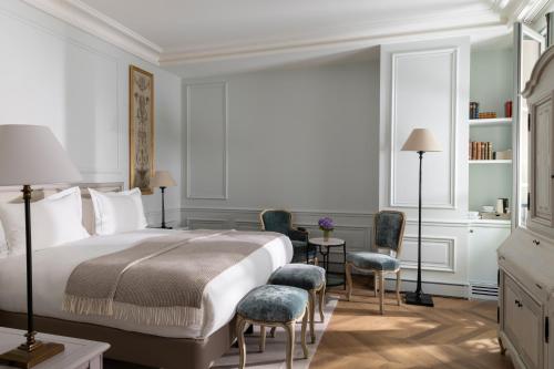 a bedroom with a bed and chairs and a desk at Hotel Du Quai Voltaire in Paris