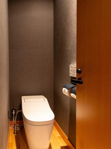 a bathroom with a white toilet and a door at Temple Hotel Takayama Zenkoji in Takayama