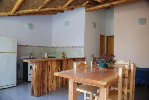 cocina con mesa de madera con sillas y nevera en Valle de Epuyen en Epuyén