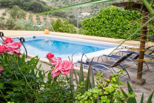 a swimming pool with pink flowers in front of it at Casa Rural Cortijos San Jose in Iznájar