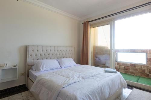 a bedroom with a white bed with a large window at Hayah Suites & Rooms in Alexandria