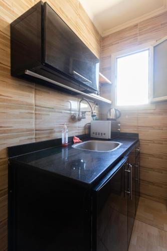 a kitchen with a black counter top and a sink at Hayah Suites & Rooms in Alexandria